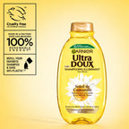Garnier Ultra Doux Camomile and Flower Honey illuminating shampoo bottle with golden liquid inside, casual hair care product.