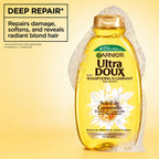 Garnier Ultra Doux camomile and flower honey illuminating shampoo bottle with light yellow liquid and floral label design