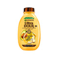 Garnier Ultra Doux Avocado and Shea Butter shampoo bottle with a natural hair care setting and fresh green leaves background.