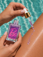 Model applying ADAY x Barbie Glow Beam Body Serum to her arm beside a pool