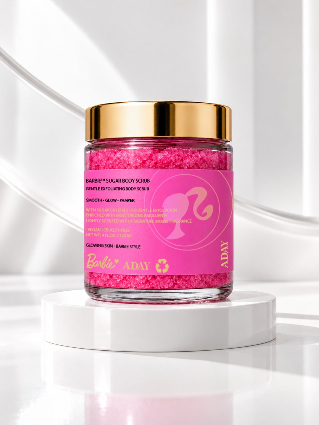 ADAY x Barbie Sugar Body Scrub, a glass jar of hot-pink scrub with a gold lid on a white pedestal