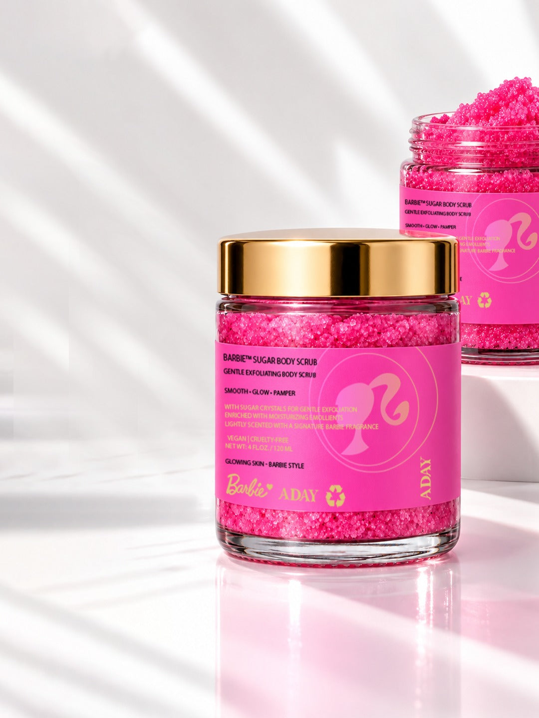 Two jars of ADAY x Barbie Sugar Body Scrub, one heaped with pink sugar crystals