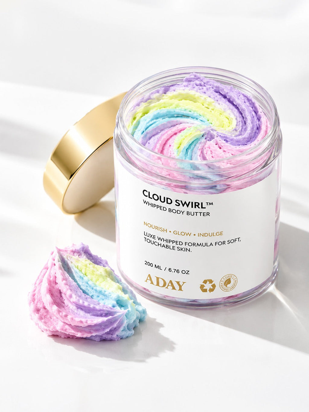 ADAY Cloud Swirl Whipped Body Butter beside a scooped dollop of the pastel rainbow butter