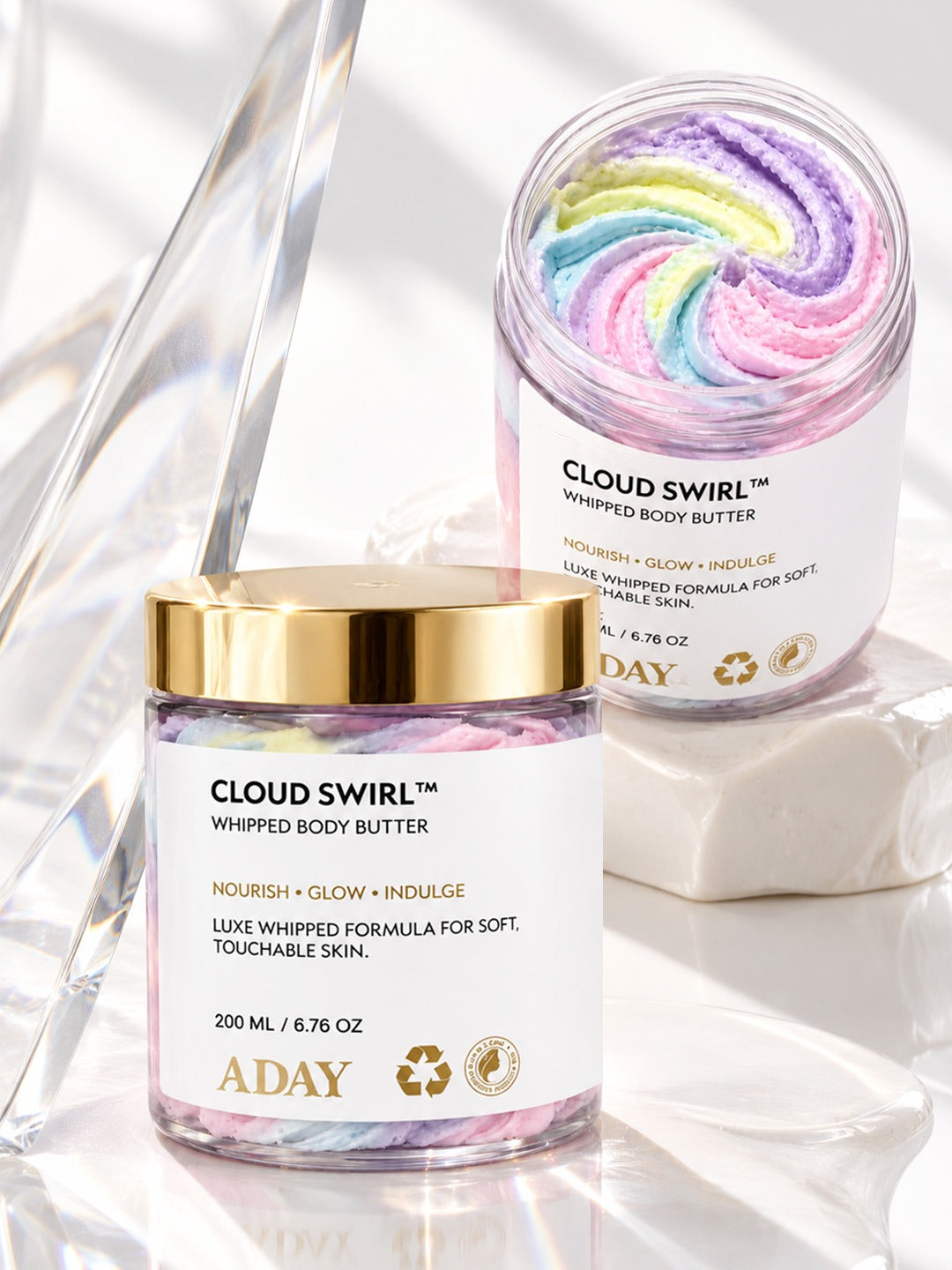 Two jars of ADAY Cloud Swirl Whipped Body Butter, one open to show the rainbow swirl