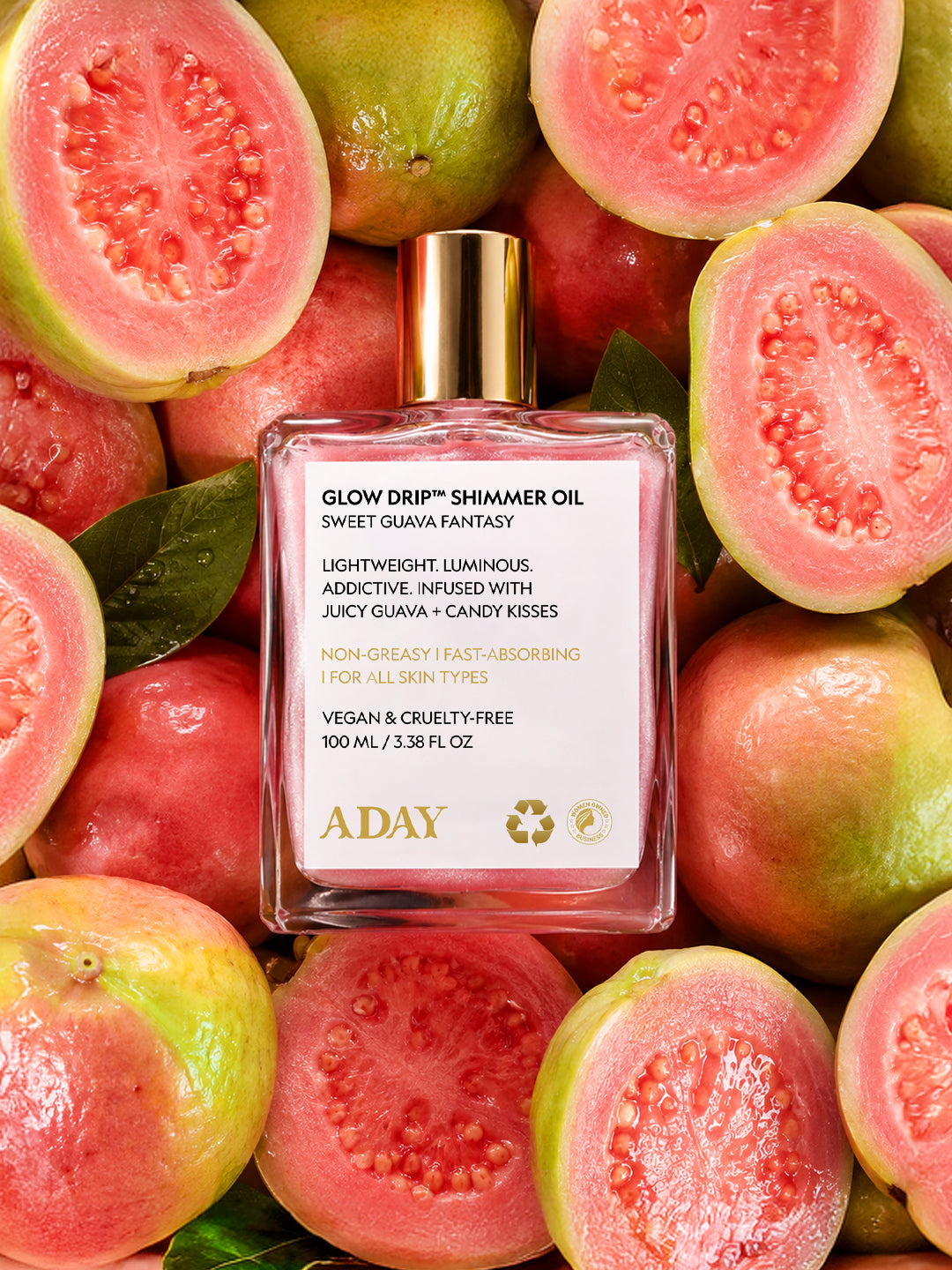ADAY Glow Drip Shimmer Oil nestled among halved fresh guavas