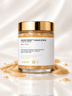ADAY Glow Frost Sugar Scrub with its gold lid resting beside it on cream silk