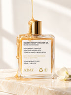 ADAY Golden Hour Shimmer Oil in Island Manoi Mood, a 100 ml gold-capped glass bottle with honey drizzling over it