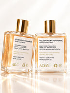 Two bottles of ADAY Golden Hour Shimmer Oil side by side on a white surface