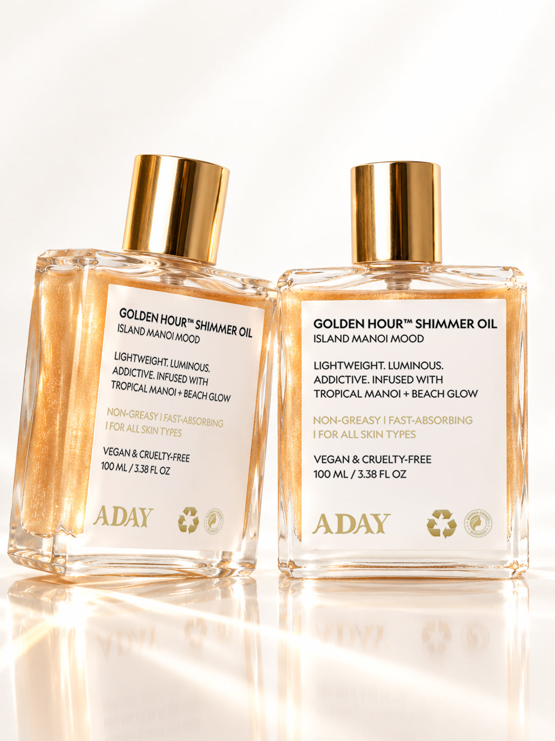 Two bottles of ADAY Golden Hour Shimmer Oil side by side on a white surface