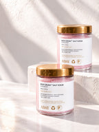 Two jars of ADAY Rosy Crush Salt Scrub on white plinths in sunlight