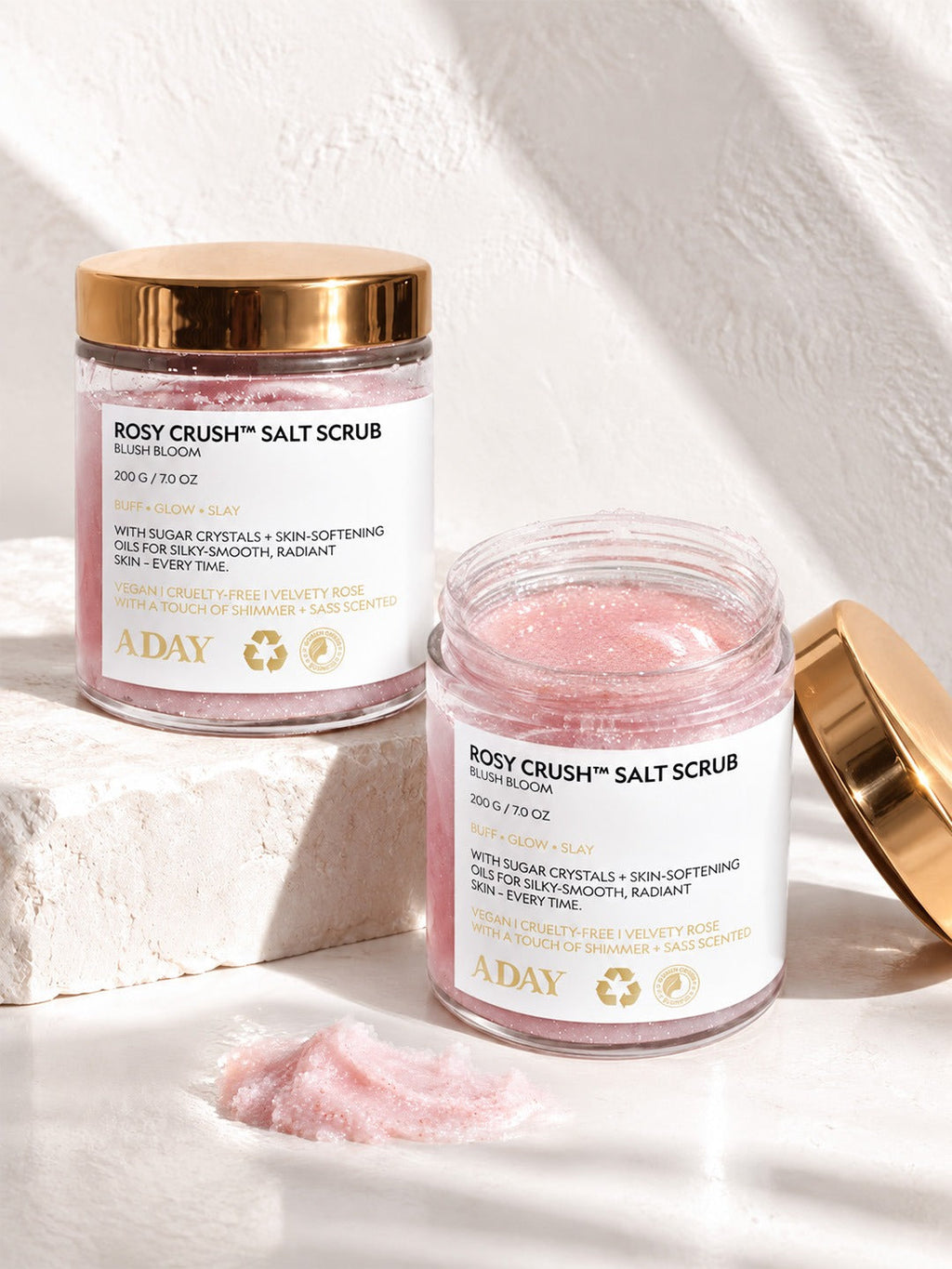 Two jars of ADAY Rosy Crush Salt Scrub, one open beside a scoop of pink scrub
