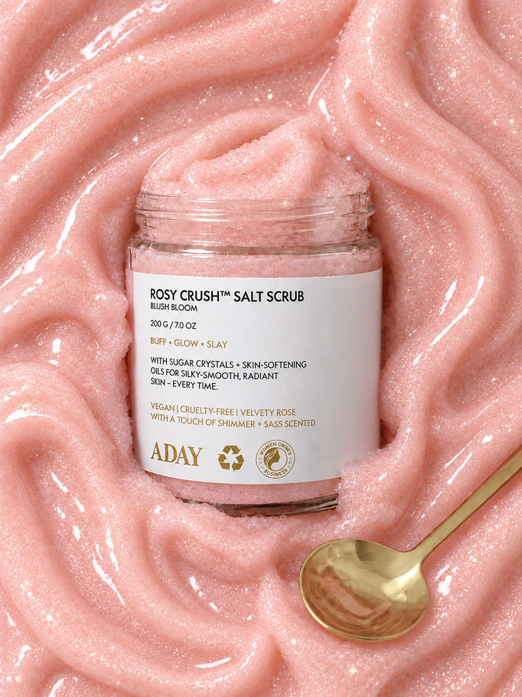 ADAY Rosy Crush Salt Scrub set in a swirl of pink scrub with a gold spoon