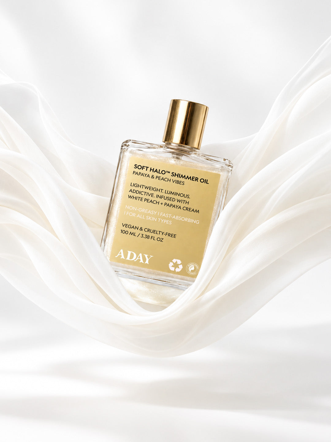 ADAY Soft Halo Shimmer Oil resting on white silk