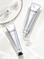 Two tubes of ADAY Silver Shimmer Toothpaste with a toothbrush and a swirl of paste