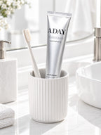 ADAY Silver Shimmer Toothpaste in a ceramic cup with a toothbrush