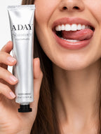 A model smiling while holding the ADAY Silver Shimmer Toothpaste