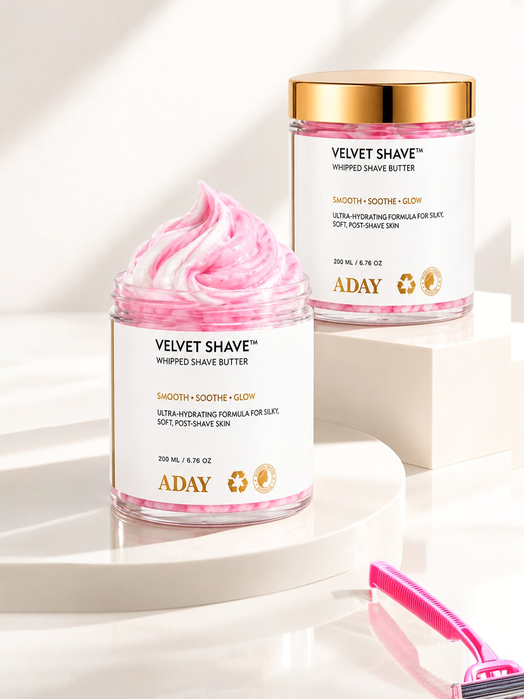 Two jars of ADAY Velvet Shave Whipped Shave Butter on white plinths, one open to show the whipped peak